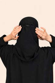 منظر خلفي لنقاب أسود بتصميم عملي وخامة ناعمة على خلفية بيج فاتح 